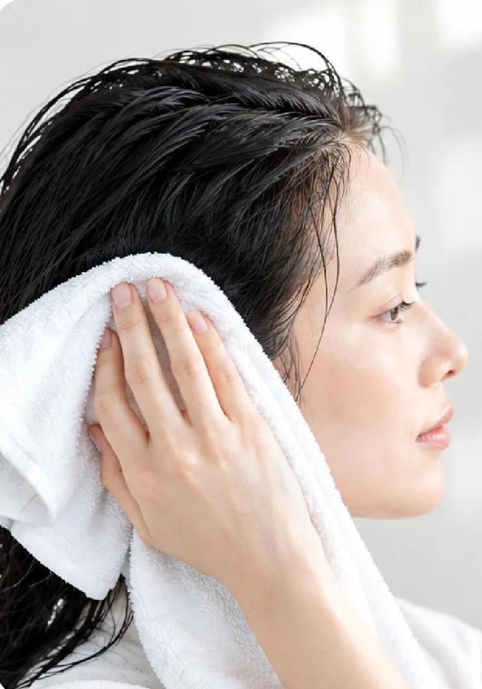 洗髪後にタオルで髪の水気をおさえる女性