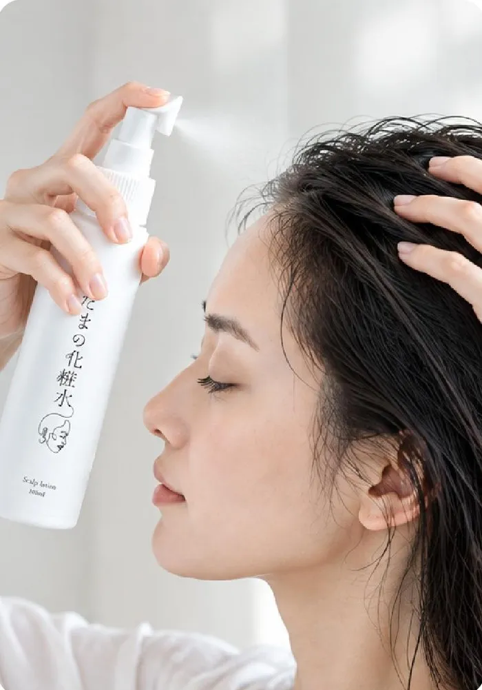 髪をかき分けて頭皮にあたまの化粧水をスプレーする女性